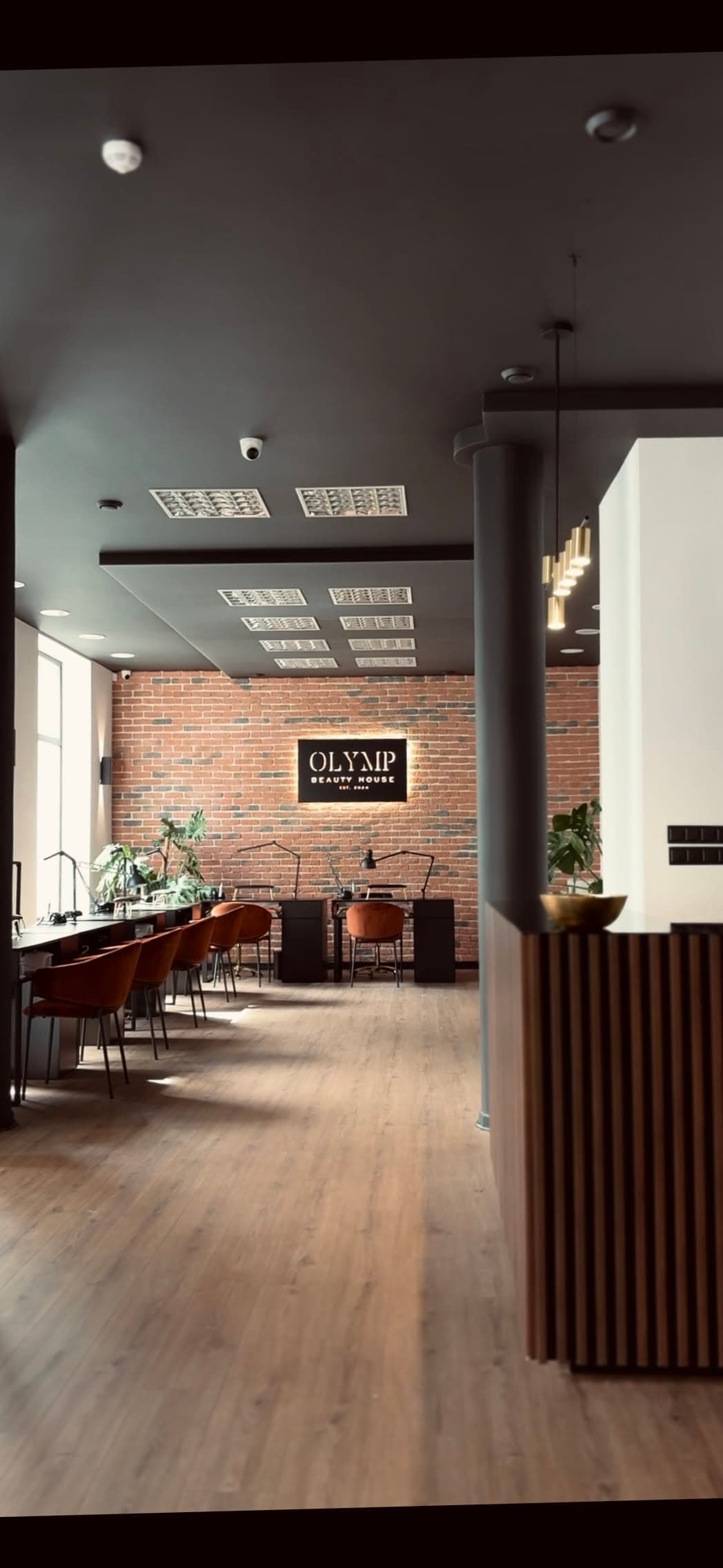 Wnętrze salonu OLYMP Beauty House w Radomiu — ceglana ściana, drewno i mosiądz